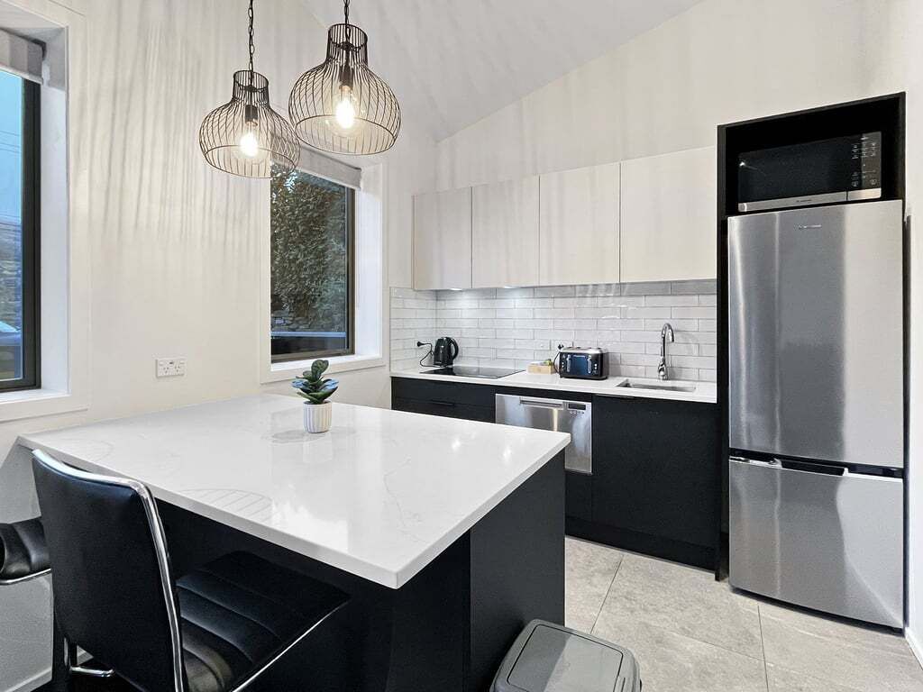 A modern kitchen with a central island, stainless steel appliances, and pendant lighting.