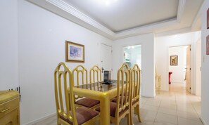 Un comedor con una mesa de vidrio y seis sillas con detalles dorados.