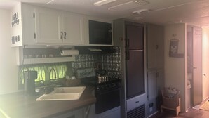 A compact kitchen with white cabinets, a stainless steel refrigerator, and a stove.