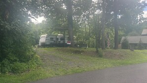 A wooded area with a trailer and a house.