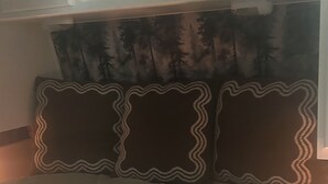 A bed with a white mattress and a headboard with a forest pattern.