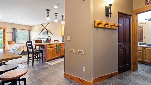 A spacious kitchen with wooden cabinets, a dining area with a table and chairs, and a large window with curtains. - Alpine Suite, Sauna, Pool Table & DT Kellogg (Kellogg)
