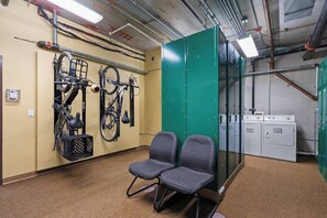 Ein Zimmer mit zwei gemusterten Stühlen, einem Fahrradständer an der Wand und einem Waschbereich mit Trocknern.