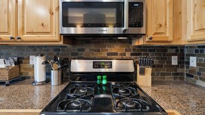 A kitchen with a Bosch microwave, a stove, and wooden cabinets. - Alpine Suite, Sauna, Pool Table & DT Kellogg (Kellogg)