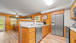 A modern kitchen with wooden cabinetry, stainless steel appliances, and a central island. - Marvelous 2-bedroom cabin located behind Dollywood. (Sevierville)