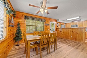 Ein Holzinterieur mit einem Esstisch, Stühlen, einem Deckenventilator und einer Küchenzeile.