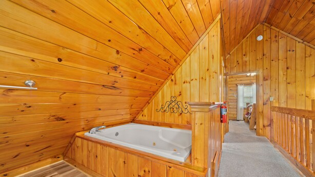 A wooden interior with a bathtub, a towel rack, and a fire extinguisher. - Marvelous 2-bedroom cabin located behind Dollywood. (Sevierville)
