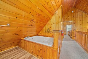 A wooden interior with a bathtub, a towel rack, and a fire extinguisher. - Marvelous 2-bedroom cabin located behind Dollywood. (Sevierville)