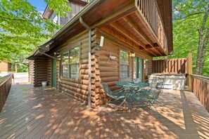 A log cabin with a deck, outdoor seating, and a window with shutters. - Marvelous 2-bedroom cabin located behind Dollywood. (Sevierville)