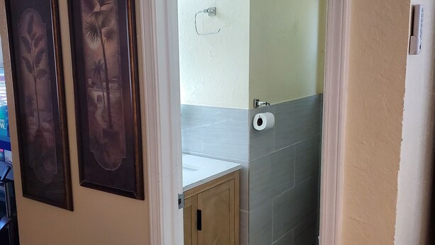A doorway leading to a bathroom with a toilet, a towel rack, and a framed picture on the wall.