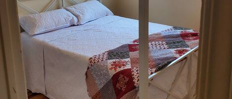 A room with a four-poster bed, a ceiling fan, and a window with blinds.