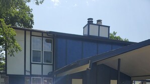 A silver car parked in a driveway with a blue building in the background.