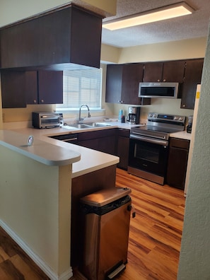 Una cocina moderna con gabinetes de madera oscura, electrodomésticos de acero inoxidable y piso de madera.