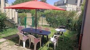 An outdoor patio with a table and chairs, a red umbrella, and a grill. - Wellness and Relaxation Studio (La Tour-du-Pin)