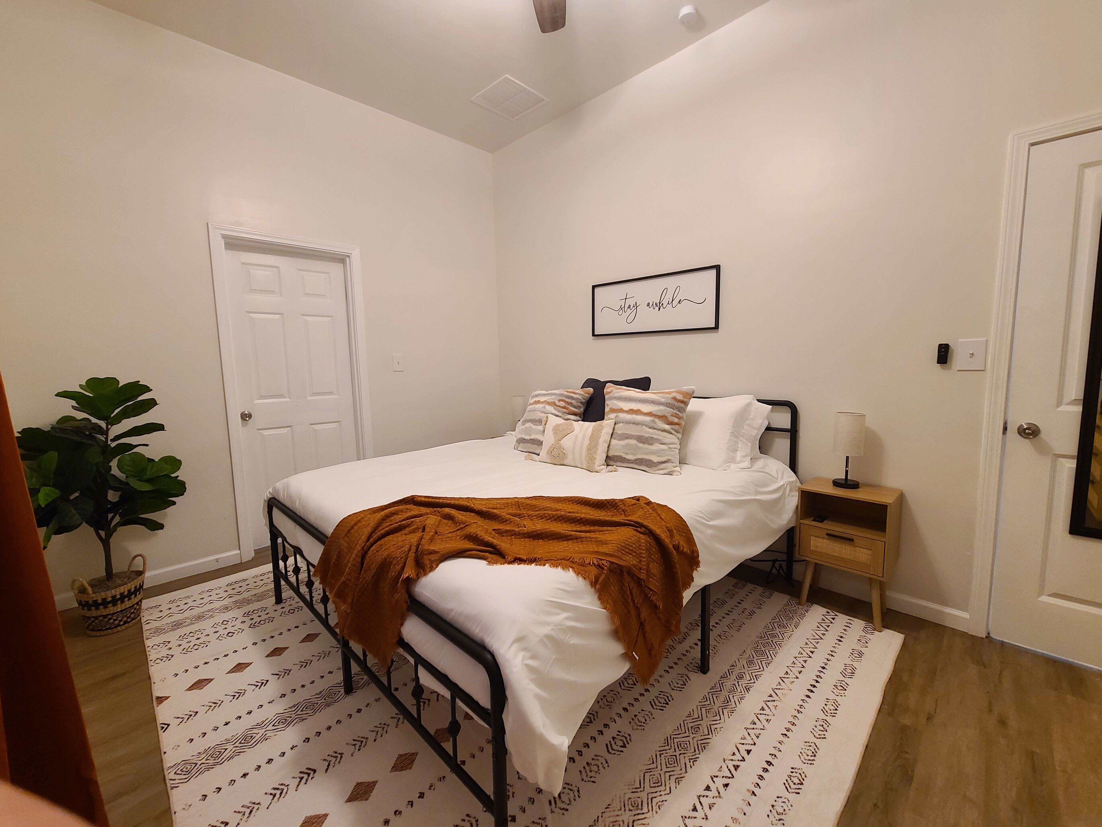 Een slaapkamer met een bed, nachtkastje en een wandlamp.