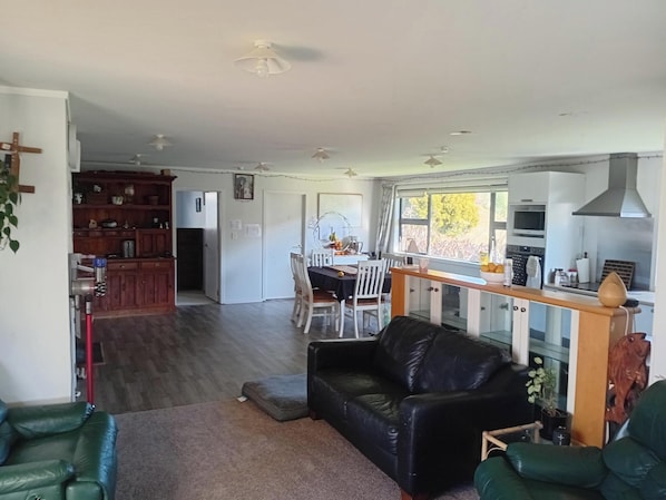 A spacious living area with a leather sofa, a dining table with chairs, and a kitchen with modern appliances.