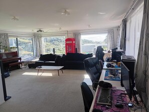 Amplia sala de estar con un sofá, una mesa de centro, una silla gamer, un escritorio con una computadora y un teléfono rojo.