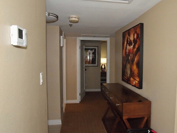 A hallway with a wooden dresser, a painting on the wall, and a thermostat on the wall. - Oceanfront View in Honolulu at The Hilton Hawaiian Village Lagoon Tower (Honolulu)