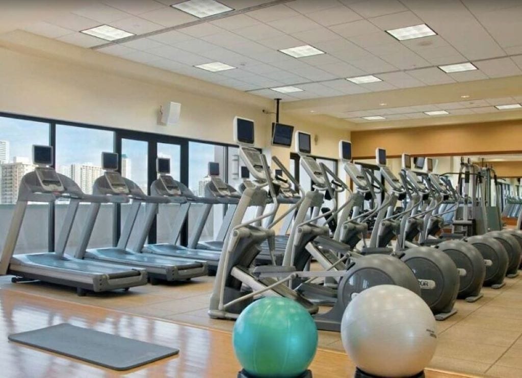 Un gimnasio con cintas de correr, elípticas y pelotas de ejercicio.