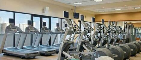 Un gimnasio con cintas de correr, elípticas y pelotas de ejercicio.