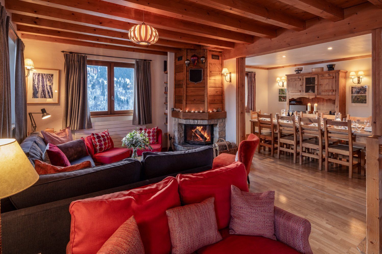 A cozy living room with a fireplace, wooden furniture, and a dining area with a table set for four.