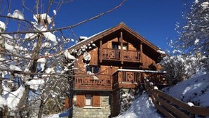 Una baita di legno con un balcone, immersa in un paesaggio innevato.