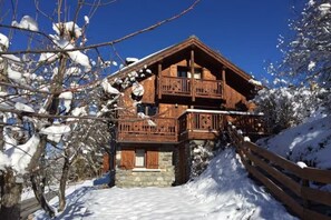 Eine Holzhütte mit Balkon, umgeben von schneebedeckten Bäumen.