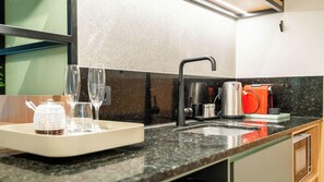 A modern kitchen with a granite countertop, a stainless steel sink, and a coffee maker.
