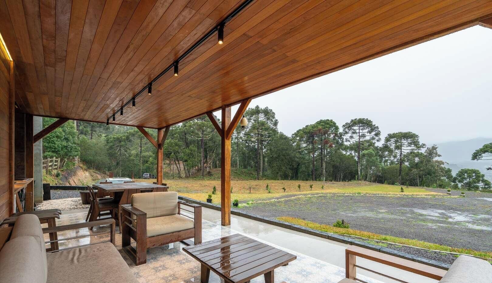 Un espacio de estar al aire libre con mobiliario de madera y vistas a un paisaje boscoso.