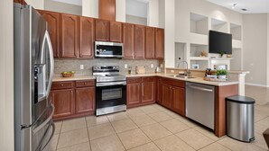 Uma cozinha moderna com eletrodomésticos de aço inoxidável, armários de madeira e painel de azulejos.