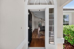 A hallway with a wooden floor leading to a living area with a sofa and a rug.