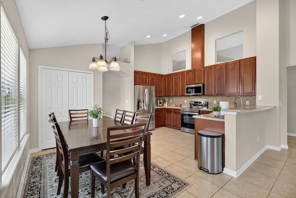 A modern kitchen with wooden cabinets, stainless steel appliances, and a dining area with a table and chairs.