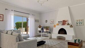 A living room with a sofa, coffee table, fireplace, and artwork on the walls.