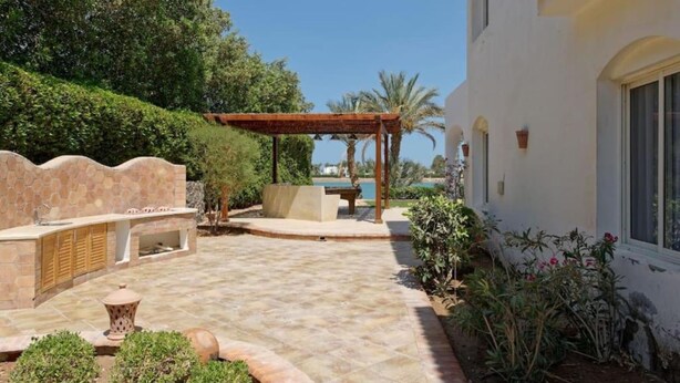 A patio area with a pergola, outdoor seating, and a view of the sea.