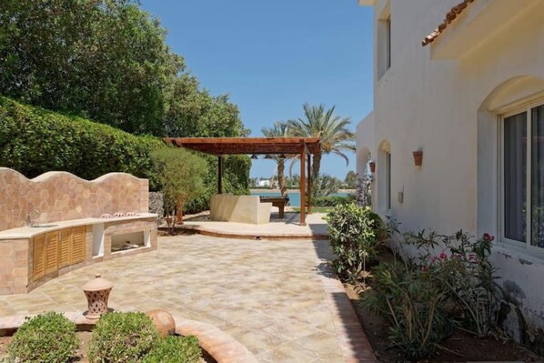 A patio area with a pergola, outdoor seating, and a view of the sea.