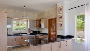 A modern kitchen with wooden cabinets, a black countertop island, and a window providing natural light.