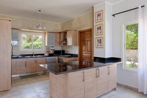 A modern kitchen with wooden cabinets, a black countertop island, and a window providing natural light.