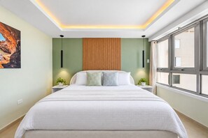 Ein modernes Schlafzimmer mit einem großen Bett, einer Wand aus Holzpaneelen und einem Fenster mit Blick auf Gebäude.