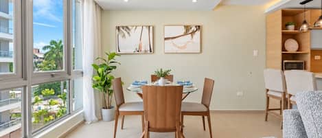 Bright and spacious open-concept living area with large windows, dining space, and modern lighting.