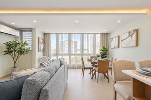 Bright and spacious open-concept living area with large windows, dining space, and modern lighting. - Remodeled Isla Verde Condo • One block to Beach (Carolina)