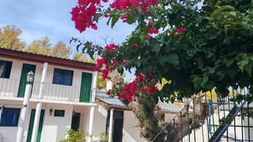 Un edificio con balcón, escalera y un árbol de flores rosadas.