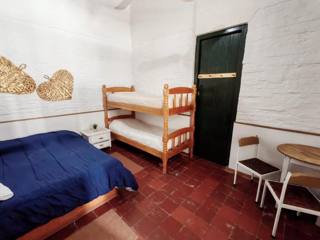 A room with a bunk bed, a single bed, a small table, and a chair.
