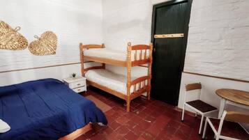 A room with a bunk bed, a single bed, a small table, and a chair.