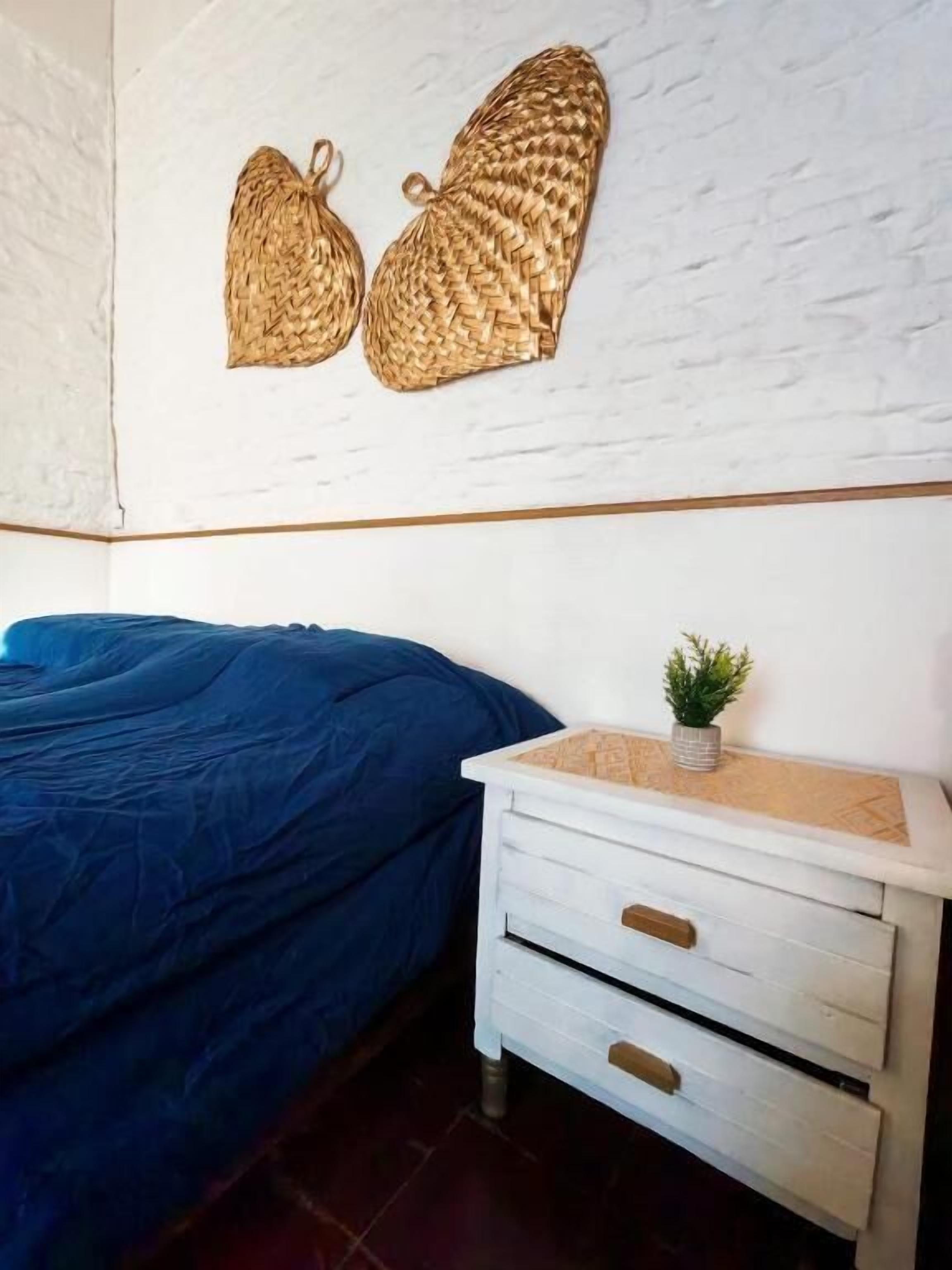 A bedroom with a bed, a white dresser with drawers, and a wall-mounted decorative item.