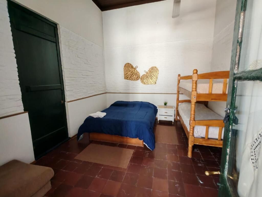 Un dormitorio con una cama, una cama litera de madera, una mesita de noche, una puerta verde y un sofá marrón.