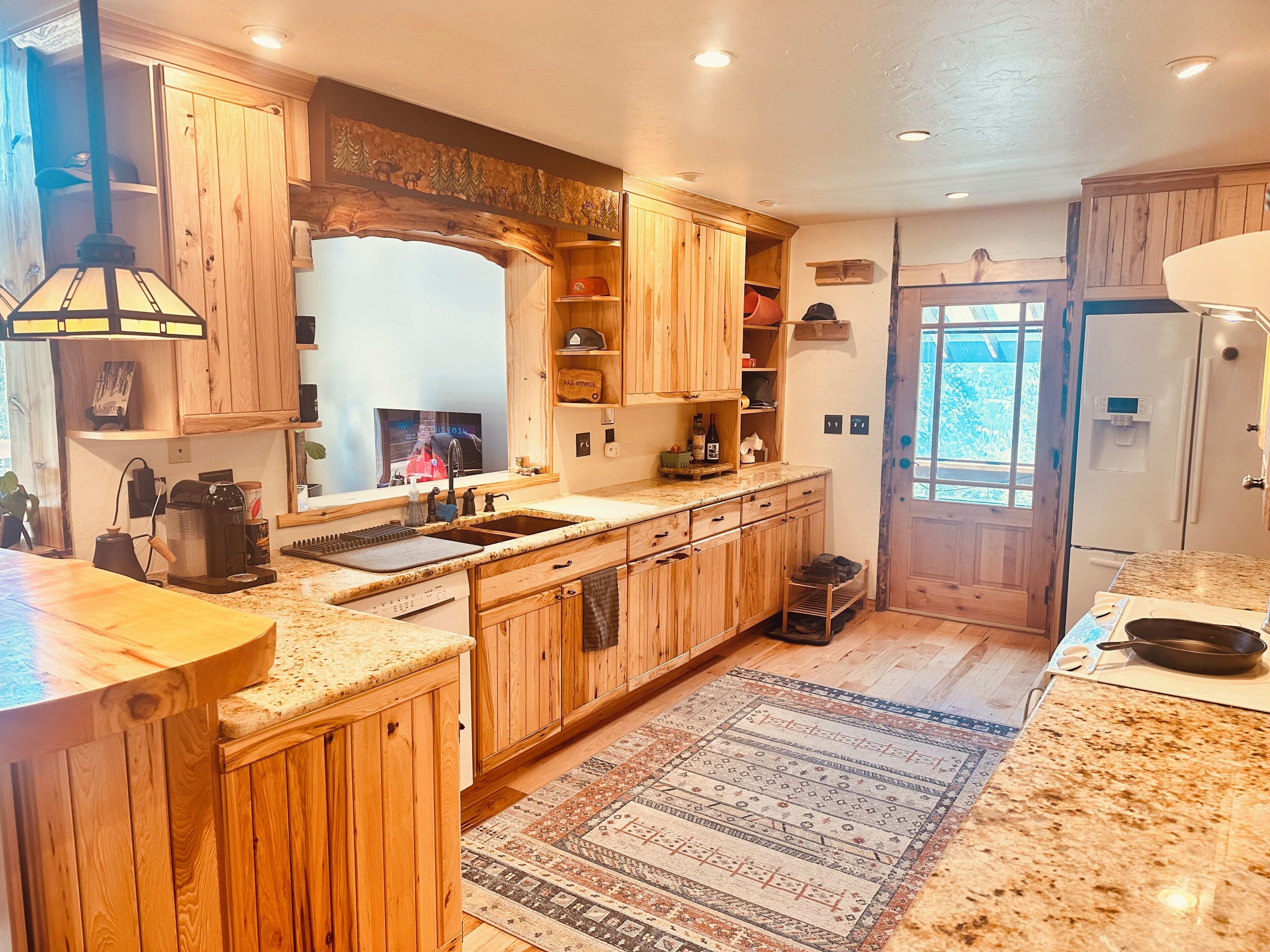 Une cuisine avec des meubles en bois, un plan de travail en granit, un four encastré et une fenêtre offrant une vue agréable.