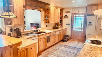 Une cuisine avec des meubles en bois, un plan de travail en granit, un four encastré et une fenêtre offrant une vue agréable.