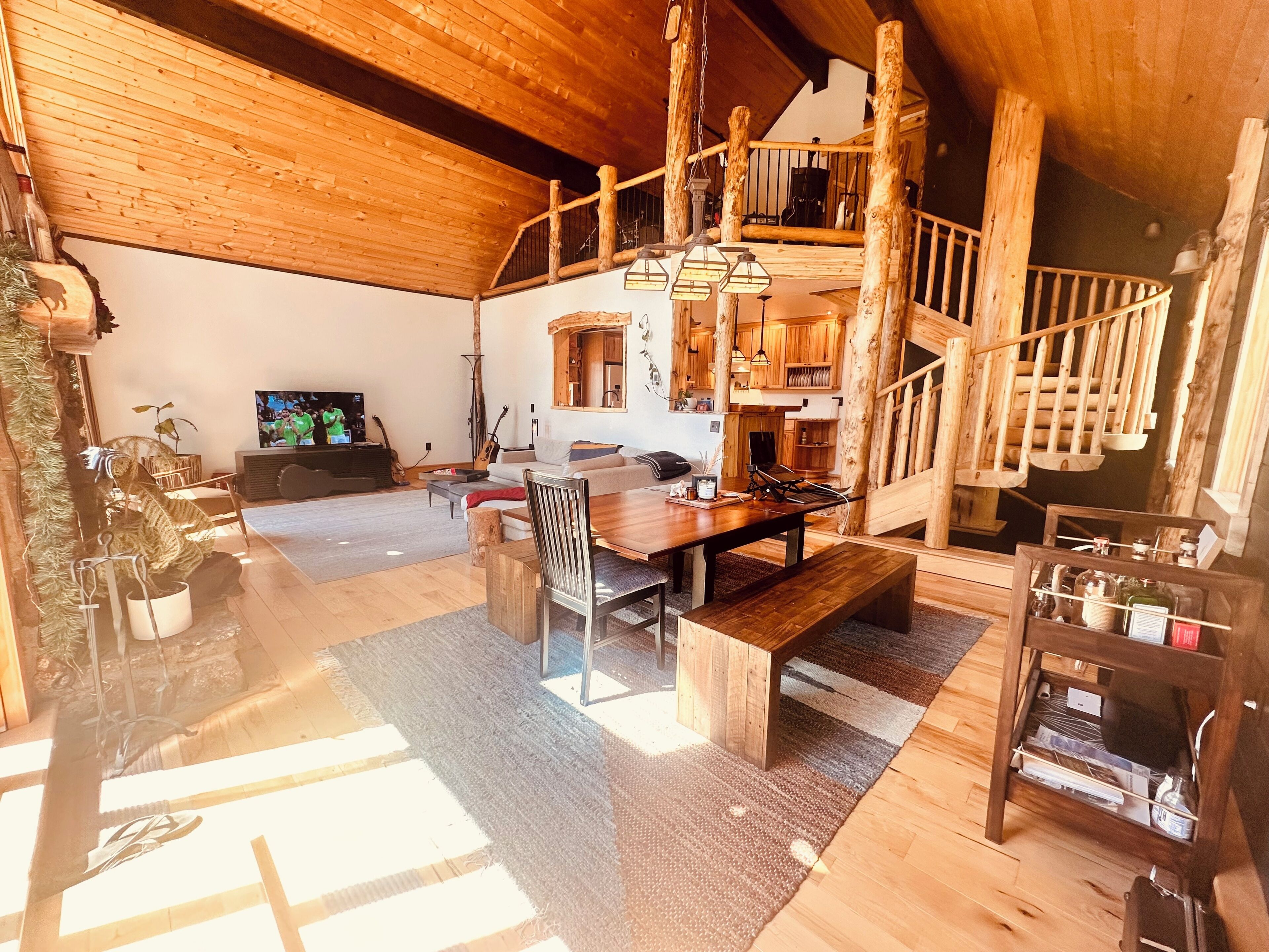 A spacious living area with a wooden staircase, a dining table, and a television.