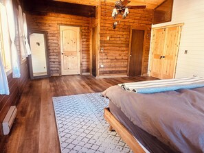 Un dormitorio de cabaña de troncos con cama, cómoda y ventilador de techo.
