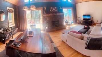 A cozy living room with a fireplace, a sofa, a dining table, and a TV.